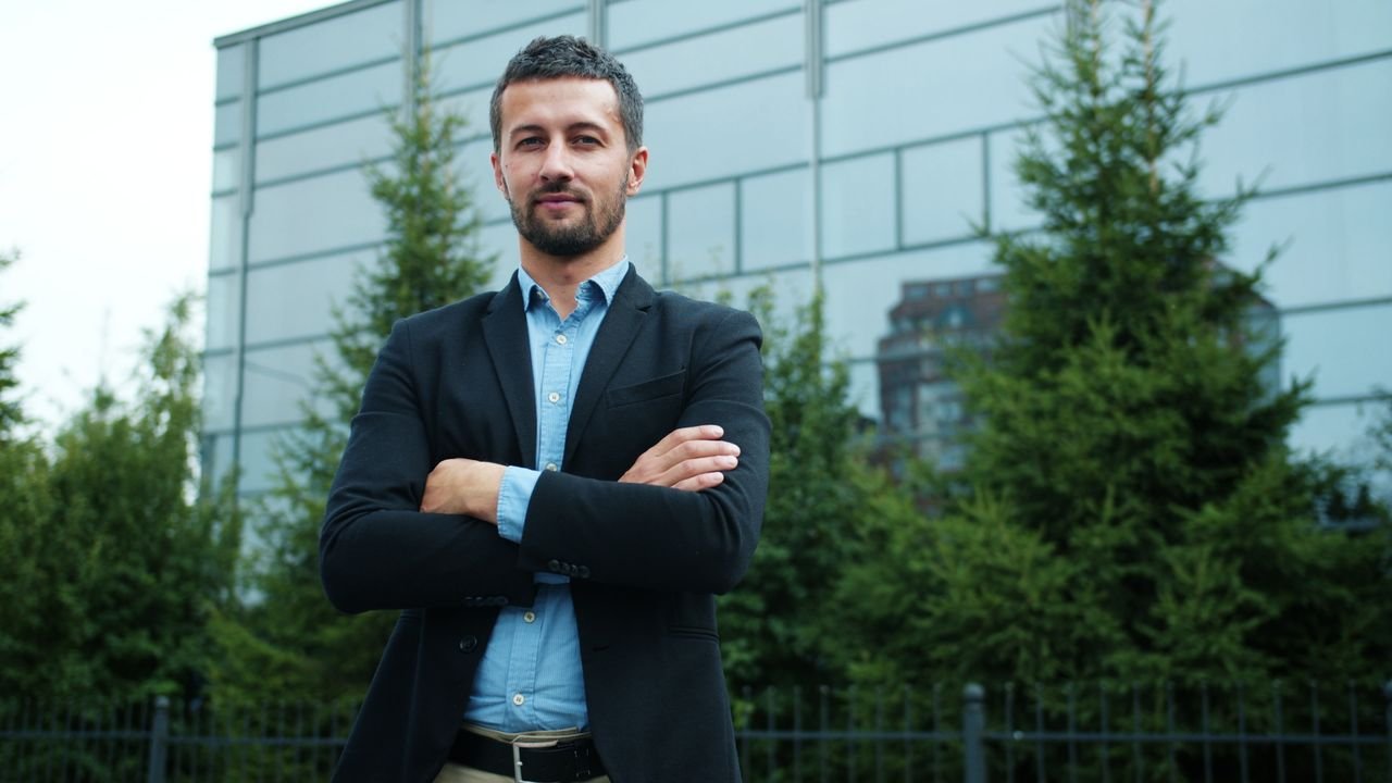 Mastering the First Impression: Your intriguing post title goes here Businessman with arms crossed in front of modern office building, outdoors.